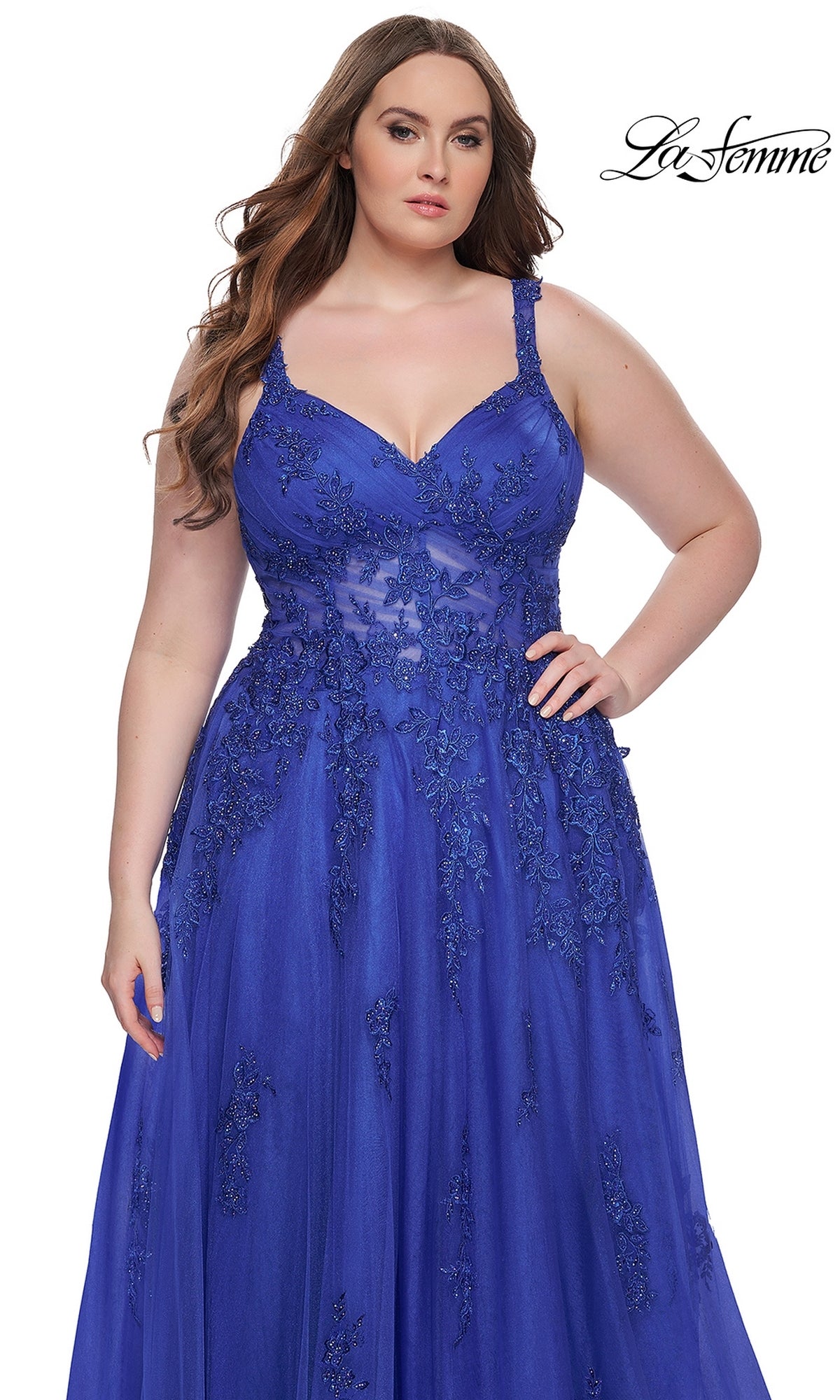 A woman stands against a white background in the La Femme Long Prom Dress 31383, a royal blue plus-size prom gown featuring sleeveless design and floral lace details.